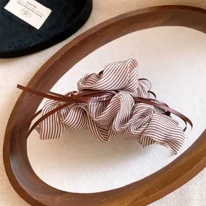 Detailed macro view of the striped ribbon bow hair claw clip in a wooden tray.