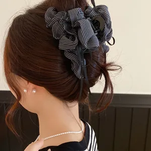 Detail shot of a ruffled striped fabric bow hair claw clip worn on an elegant updo