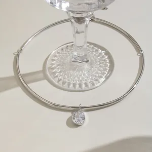Elegant detail showing a silver stainless steel choker with a pear-shaped clear crystal pendant