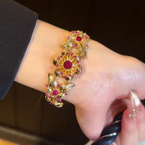 Detailansicht eines goldenen Vintage-Armbands mit Blumen- und Schmetterlingsmotiv und Steinen.