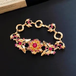 Detailansicht eines Vintage-Goldarmbands mit rosa Strasssteinen und Blumenmuster