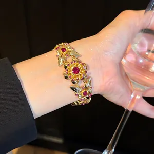 Nahaufnahme eines Vintage-Goldarmbands mit rosa Kristallen und Blumen-Schmetterlings-Design