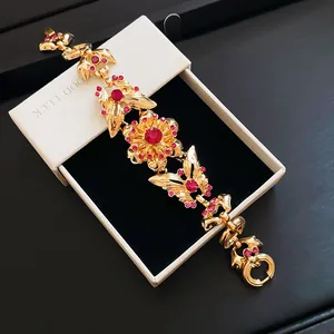 Vintage goldfarbenes Armband mit rosa Strass-Schmetterling und Blumen auf Geschenkbox.