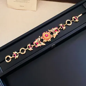 Detailansicht eines Vintage-Goldarmbands mit Schmetterlingen und roten Strasssteinen.