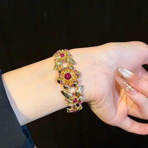 Nahaufnahme eines Vintage-Armbands mit goldenen Schmetterlingen, Blumen und rosa Steinen