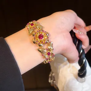 Nahaufnahme des Vintage-Goldarmbands mit Schmetterling, Blumen und rosa Strasssteinen.