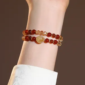 Close-up of a double-layered beaded bracelet with red and yellow crystals on a model's arm