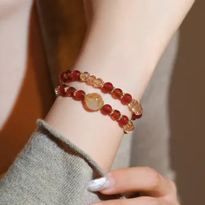 Detailed macro shot of a double-layer beaded bracelet with red crystals and amber stones