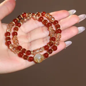 Detailed macro view of a double-layer beaded bracelet featuring red and amber crystals.