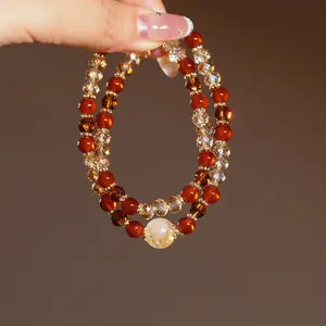 Close-up of double-layered beaded bracelet with red and amber crystal beads