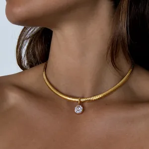 Nahaufnahme einer goldenen Schlangenkette mit rundem Zirkonia-Anhänger am Hals
