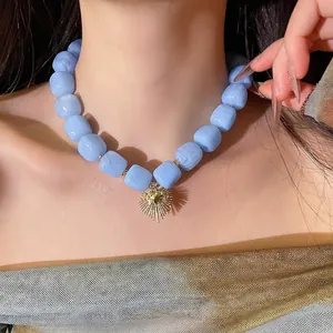 Chic blue resin square beaded necklace featuring a golden sunburst heart pendant worn by model