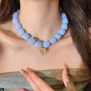 Macro view of a stylish blue resin square bead necklace featuring a gold heart pendant.