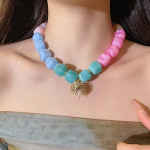 Detailed view of a colorful resin bead necklace with a gold heart pendant on a model.