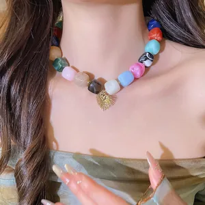 Close-up of vibrant square resin beads with a gold heart sunburst pendant necklace