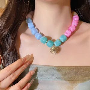 Close-up detail of a colorful resin beaded necklace with golden heart pendant on neck