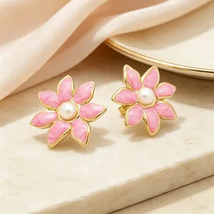 Gros plan sur des boucles d'oreilles fleurs en émail rose avec perle et placage d'or