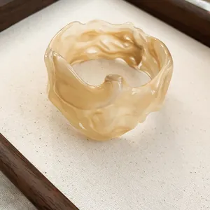 Macro view of beige wavy resin bangle with organic lava-like texture and irregular edges