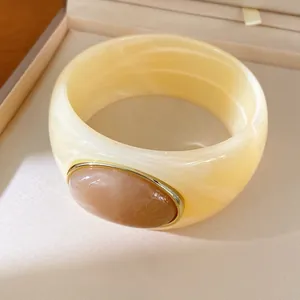 Detailed view of a cream resin chunky bangle featuring a rose-colored oval stone.