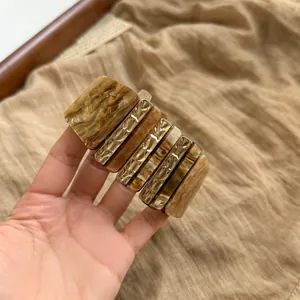 Primer plano de una pulsera geométrica gruesa con segmentos de resina ámbar y oro.