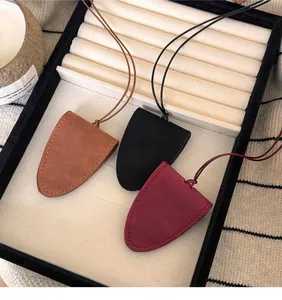 Gros plan de trois colliers porte-lunettes en cuir rétro en marron, noir et rouge