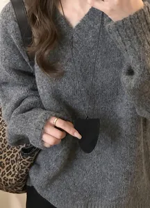 Gros plan d'un collier porte-lunettes en cuir noir porté sur un pull gris en maille