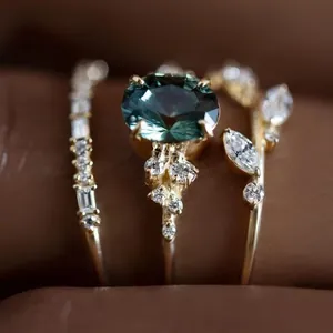 Dettaglio macro di un set di tre anelli di fidanzamento con gemma petrolio e diamanti