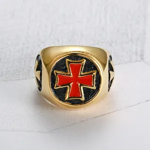 Nahaufnahme eines goldenen Rings aus Titanstahl mit einem leuchtend roten Kreuz auf Schwarz