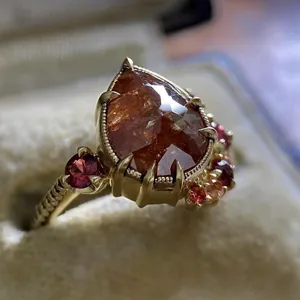 Close-up detail of vintage pear-cut orange zircon engagement ring with gold band