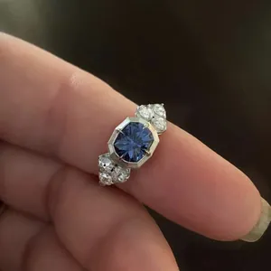 Macro view of a silver alloy engagement ring with a large blue zircon and side stones