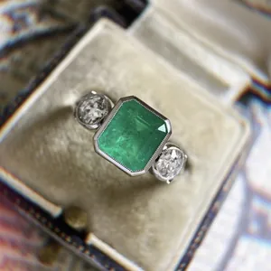 Detailed close-up of vintage style emerald-cut green zircon engagement ring in box