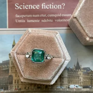 Detailed macro view of an emerald green square zircon ring set in a pink velvet gift box