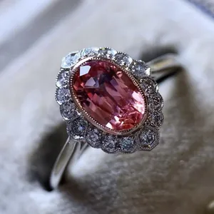 Macro detail of vintage silver-tone ring featuring a pink oval gemstone with halo