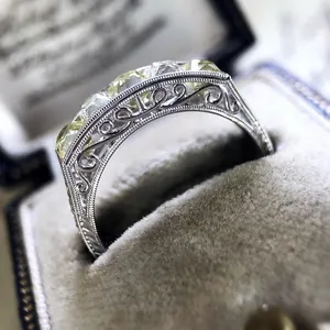 Detail macro view of vintage style silver engagement ring with filigree and yellow zircon stones.