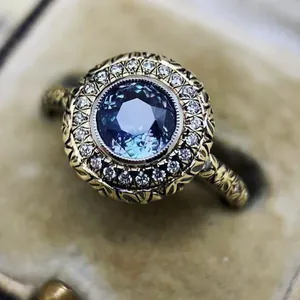 Close-up of vintage engagement ring with blue gemstone and intricate gold band detail.