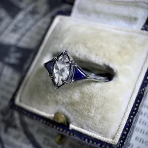Close-up of vintage engagement ring with marquise clear stone and blue trillion accents