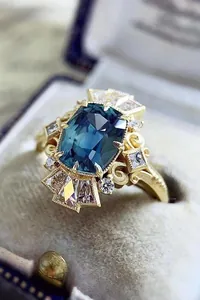 Macro detail of a vintage gold engagement ring with a large blue cushion-cut zircon.