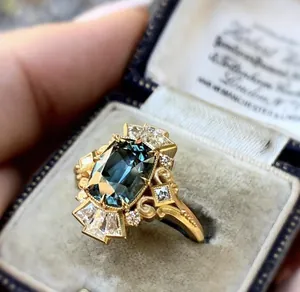 Detailed macro view of a vintage gold-tone ring featuring a teal emerald-cut center stone