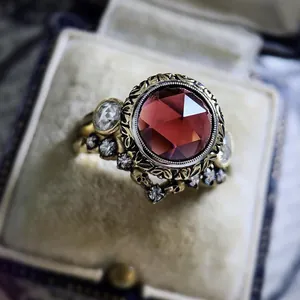 Detailed macro view of vintage gold ring featuring a large red zircon and skull accents