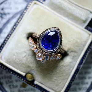 Close-up of vintage pear-cut blue zircon ring with V-shaped diamond band