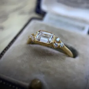 Close-up detail of a vintage emerald-cut zircon engagement ring in a gold bezel setting.
