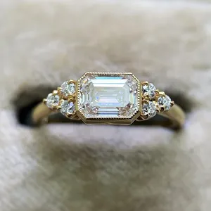 Macro detail of emerald-cut zircon engagement ring with gold finish and bead edge