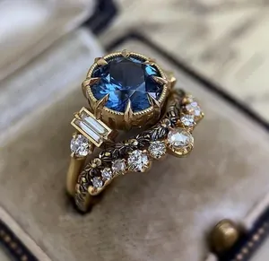 Detailed view of gold-tone engagement ring set with large blue stone and filigree band