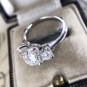 Vista macro detallada de un anillo de compromiso de plata con tres circonitas brillantes.