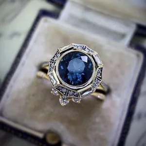 Detailed close-up of a vintage-style gold ring featuring a large blue sapphire-like stone