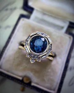 Close-up of vintage Art Deco engagement ring with a deep blue gemstone and gold setting.