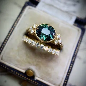 Macro view of a vintage style emerald green gemstone engagement ring set in a jewelry box