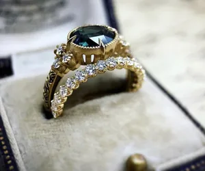 Close-up of vintage engagement ring set with dark green stone and zircon accents