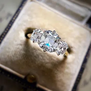 Close-up of cushion-cut cubic zirconia three-stone engagement ring in gold-tone alloy