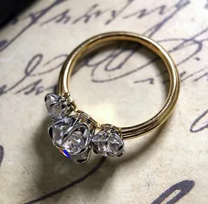 Detalle de un anillo de compromiso clásico con tres piedras de circón y banda dorada